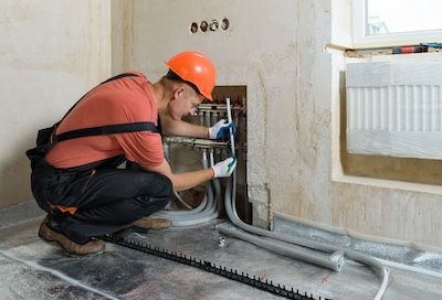 pipefitter adds insulation to pipes in wall