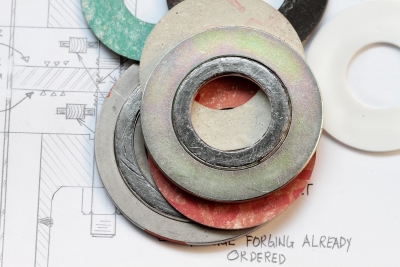 pile of asbestos gaskets laid on blueprints.